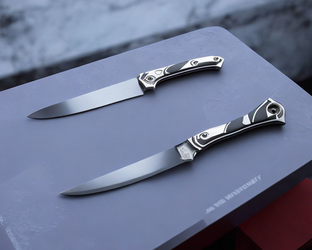 Patterned handle folding knives on stone surface: elegant and precise craftsmanship