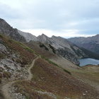 Overcast rugged mountain landscape with steep slopes and winding road.