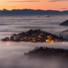 City skyline above clouds at sunset with snow-capped mountains