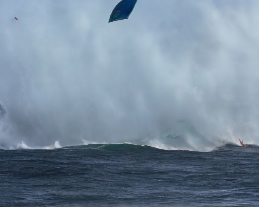 Windsurfing sail above turbulent ocean with foamy waves under cloudy sky