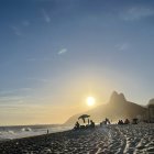 Person in Cape Facing Sunrise over Serene Mountain Landscape