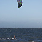 Windsurfing sail above turbulent ocean with foamy waves under cloudy sky