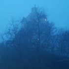 Ethereal castle on misty blue mountains under twilight sky