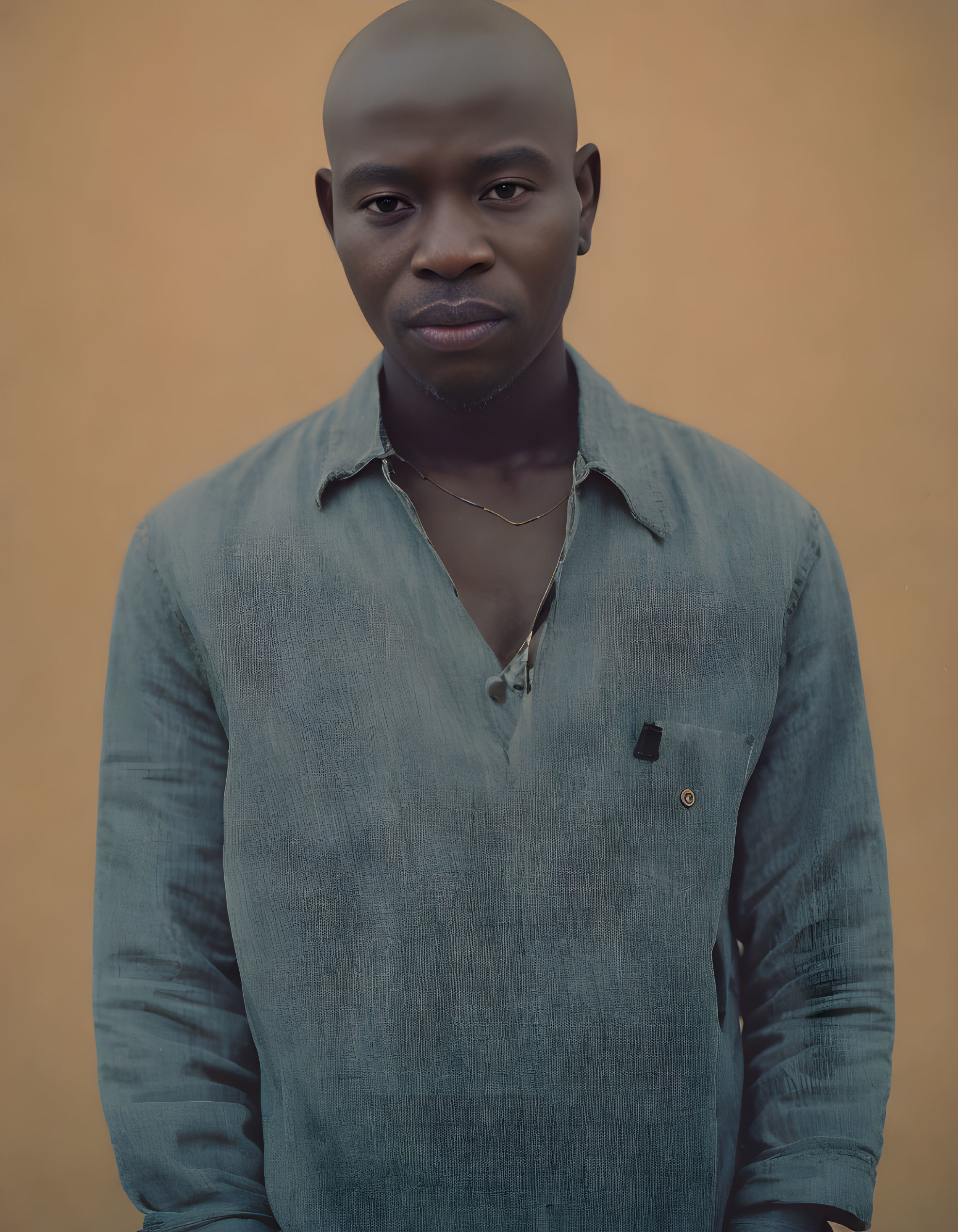 Bald person in blue shirt against tan background