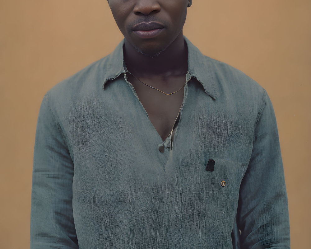 Bald person in blue shirt against tan background