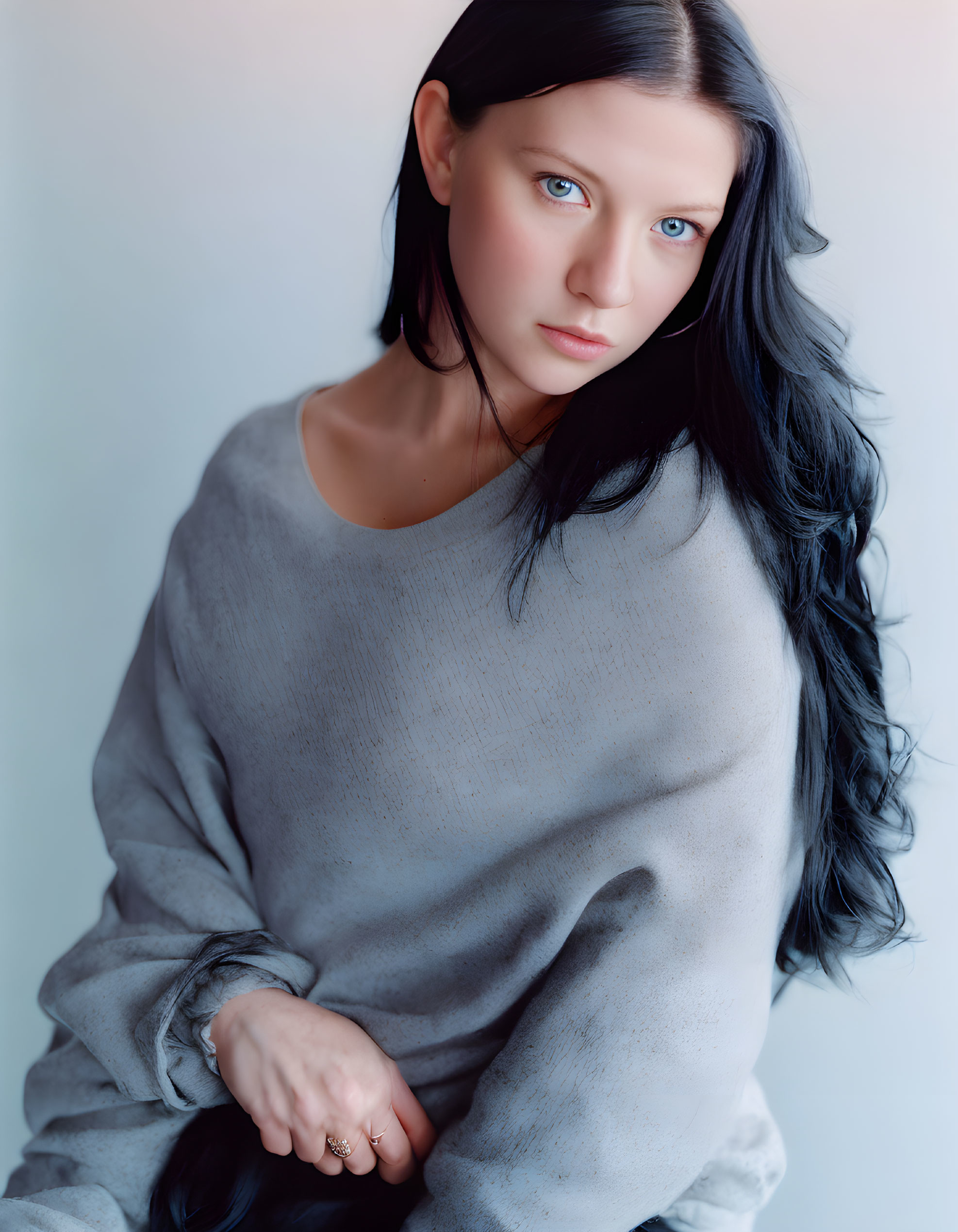 Portrait of woman with long black hair and blue eyes in gray sweater