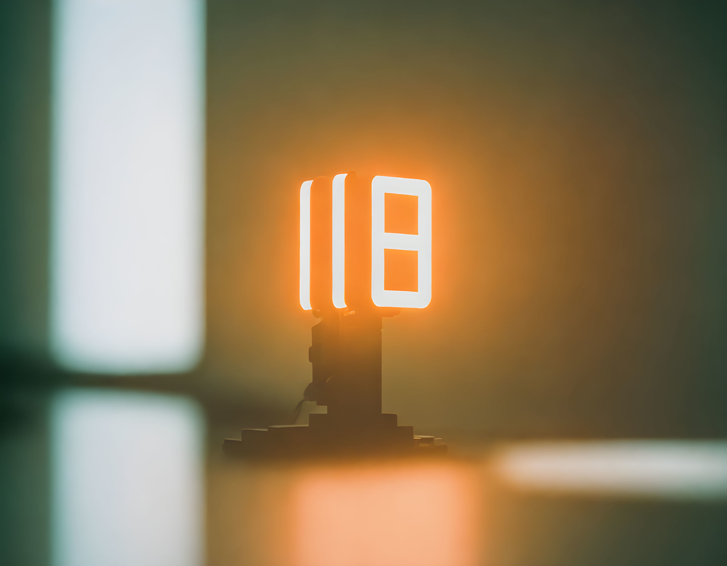 Glowing neon pause symbol sign on pedestal with soft focus background