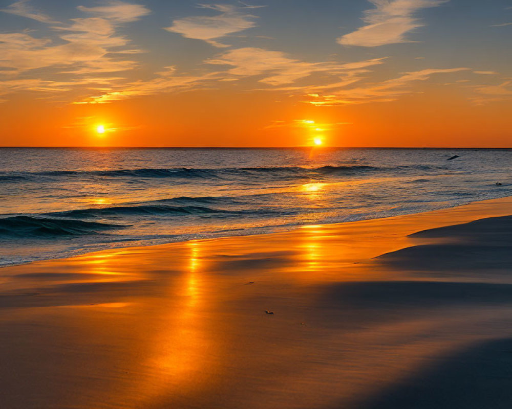 Vibrant sunset over ocean with sun reflecting on water and wet sand, bird in flight.