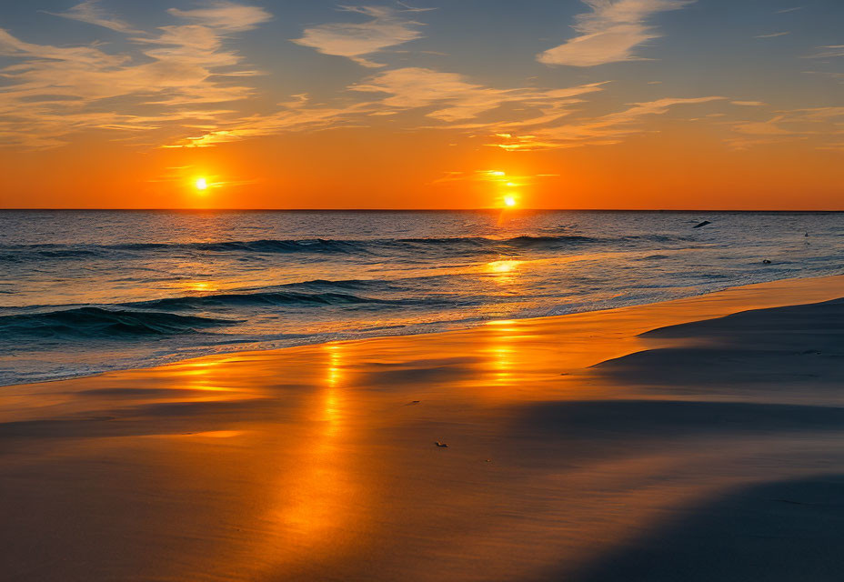 Vibrant sunset over ocean with sun reflecting on water and wet sand, bird in flight.