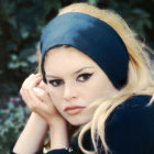 Woman with Blue Headscarf and Pearls Staring at Viewer on Green Background