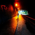 Silhouetted figures with glowing blue umbrella on dimly lit street