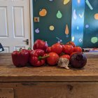 Fresh Tomatoes, Peppers, and Eggplants on Wooden Surface with Twinkling Light Background