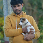 Young boy with dark hair hugging cat in mustard-yellow jacket