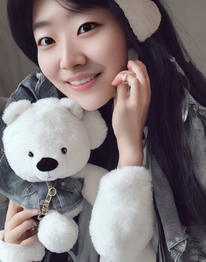 Smiling person in denim jacket with teddy bear and earmuffs