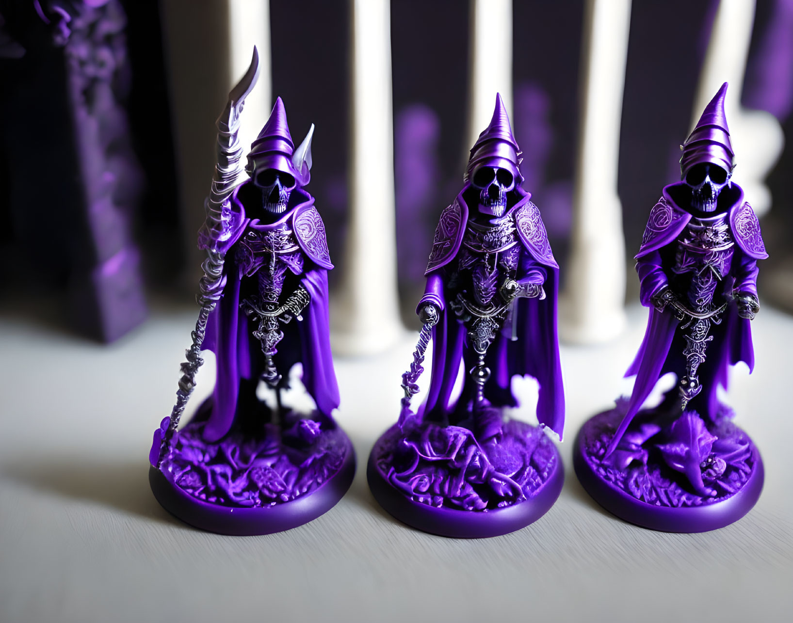 Three detailed purple fantasy character figurines with cloaks and armor, set against white cylindrical objects