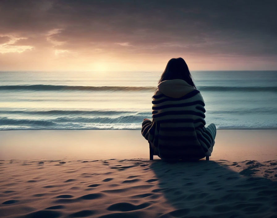 Person in Striped Sweater Contemplating Ocean at Sunset Beach