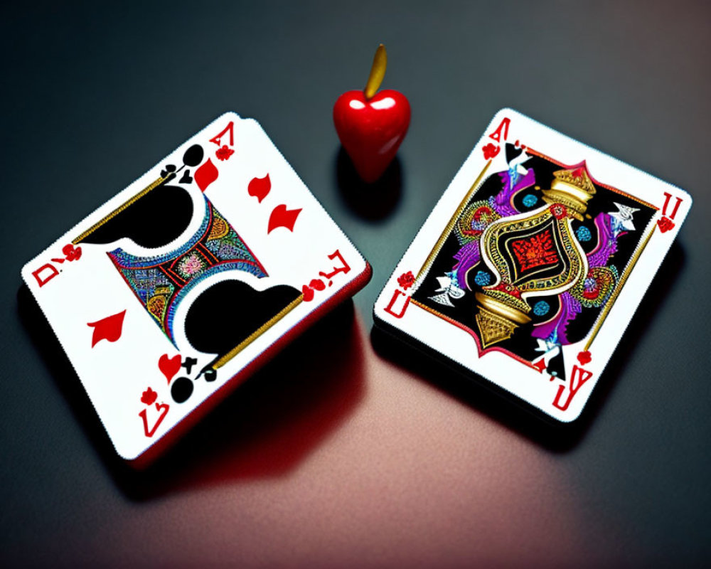 Playing cards Queen of Hearts and King of Spades with cherry token on dark surface