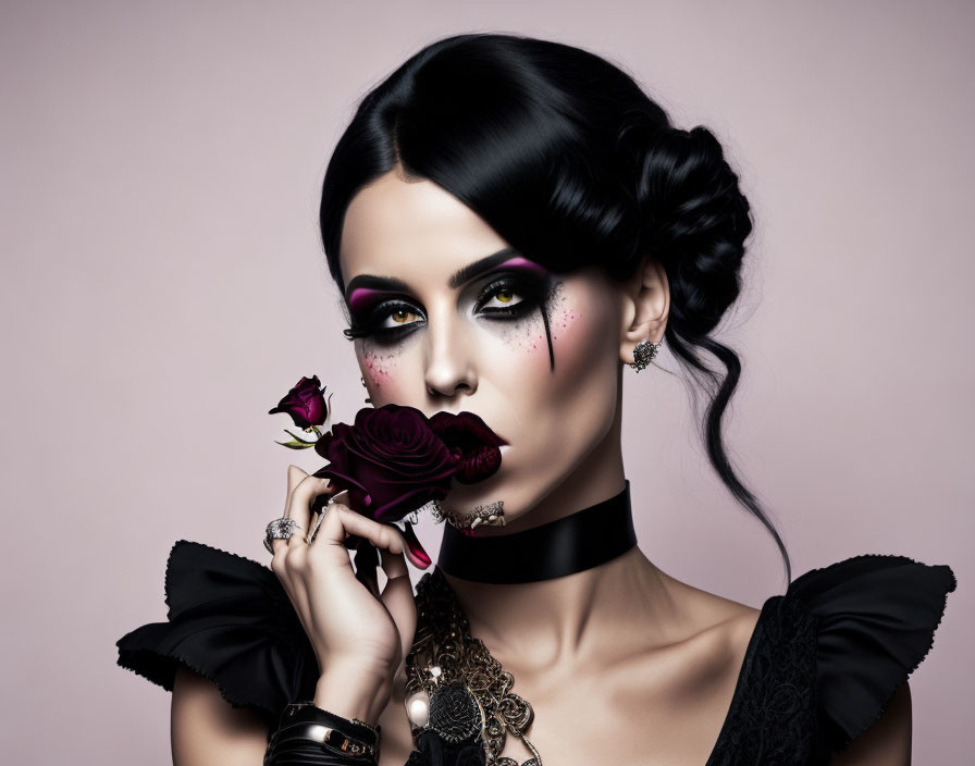 Dark-haired woman with updo, dramatic makeup, black choker, holding rose on pink background