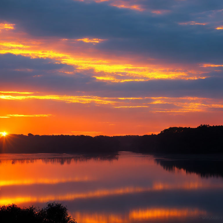 Vibrant sunrise reflections on calm lake and treelined horizon