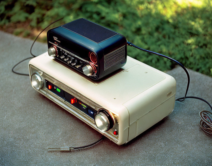 Vintage beige projector with black speaker on concrete, grass surroundings