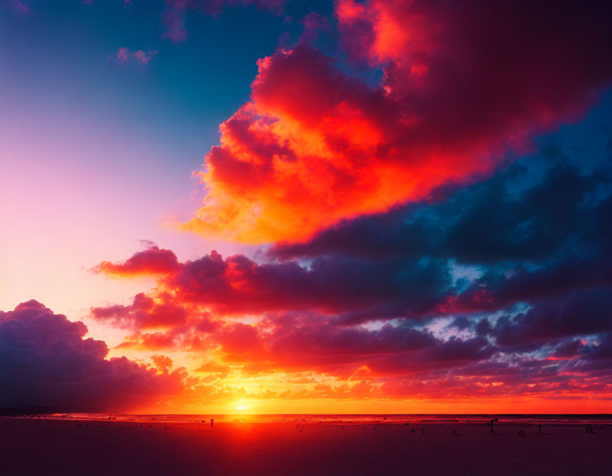 Fiery red and orange sunset over beach with silhouettes