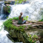 Woman in Blue Dress Contemplating by Vibrant Waterfall