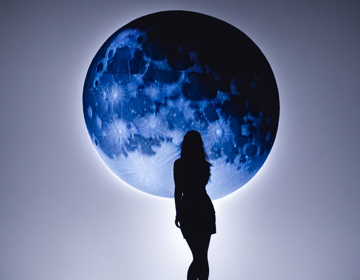 Person's silhouette before large glowing blue moon representation