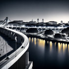 Monochrome cityscape with curved bridge, river, streetlights, treetops & buildings