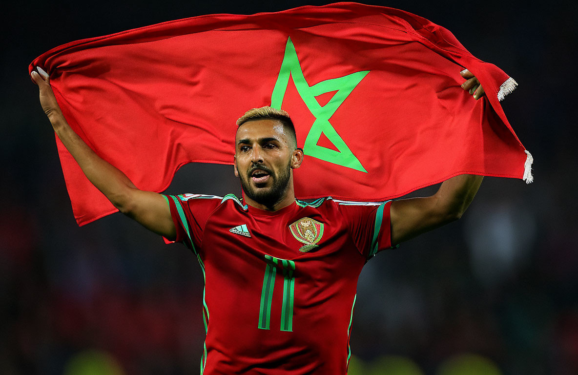 Soccer player in red jersey with green star emblem holding flag