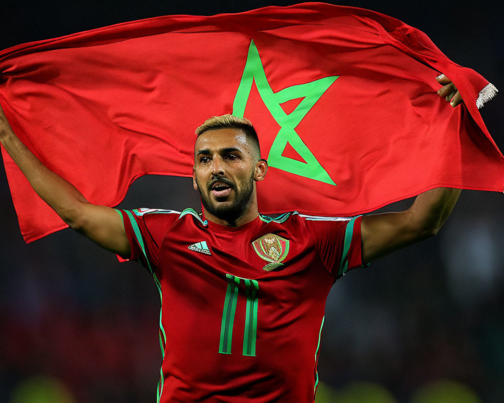 Soccer player in red jersey with green star emblem holding flag