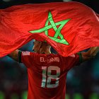 Soccer player in red jersey with green star emblem holding flag