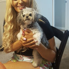 Blonde woman with blue eyes holding golden dog in ornate setting