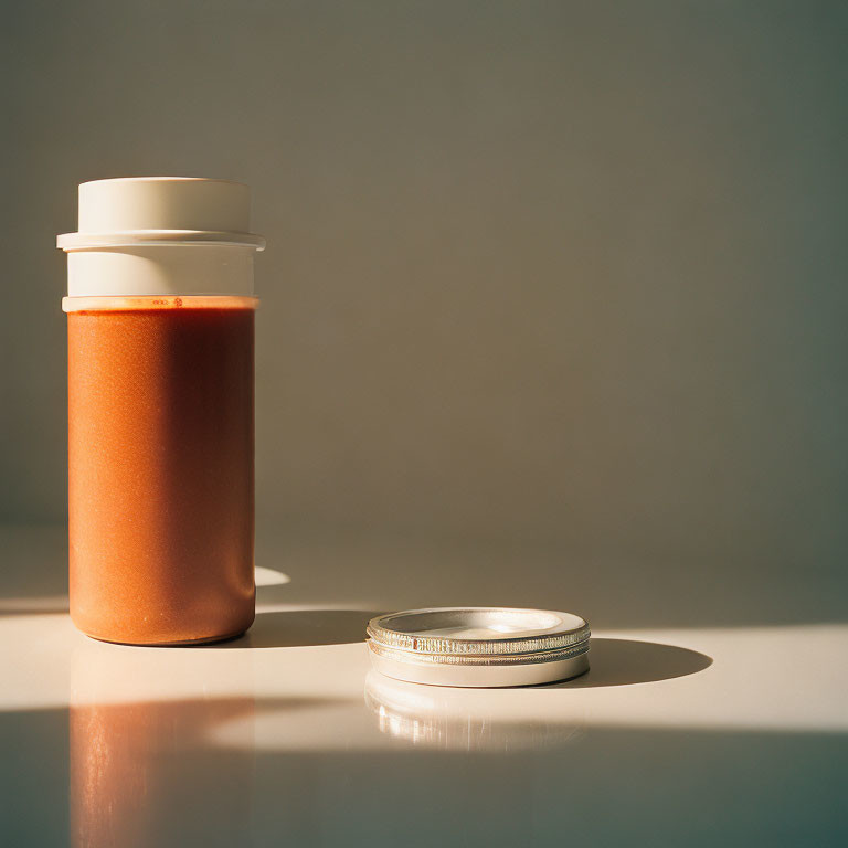 Creamy brown substance in jar with silver lid under soft light