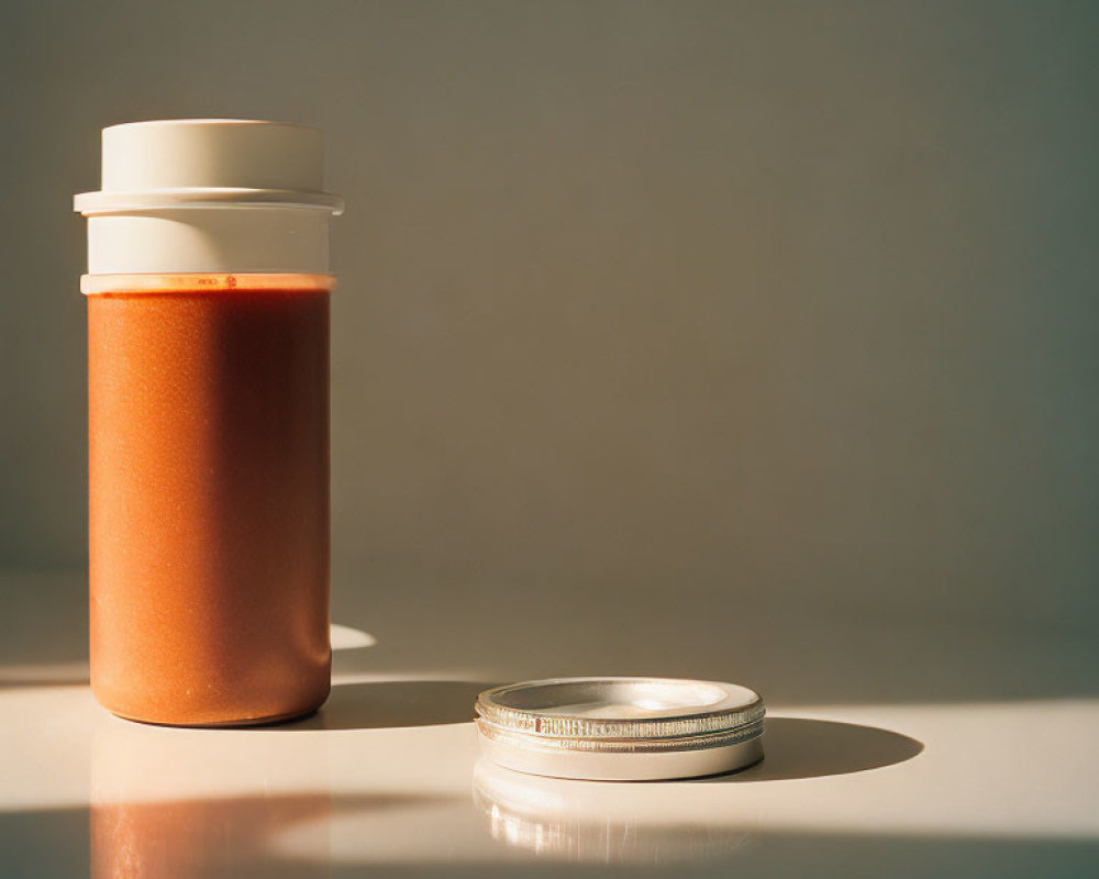 Creamy brown substance in jar with silver lid under soft light