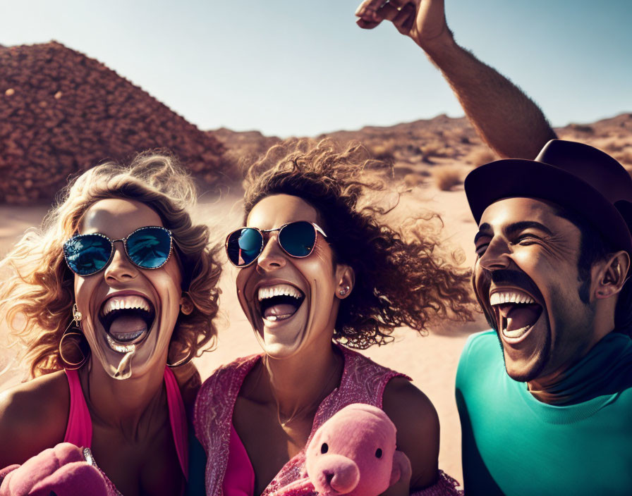 Three friends in sunglasses with plush pigs, laughing in sunny desert.