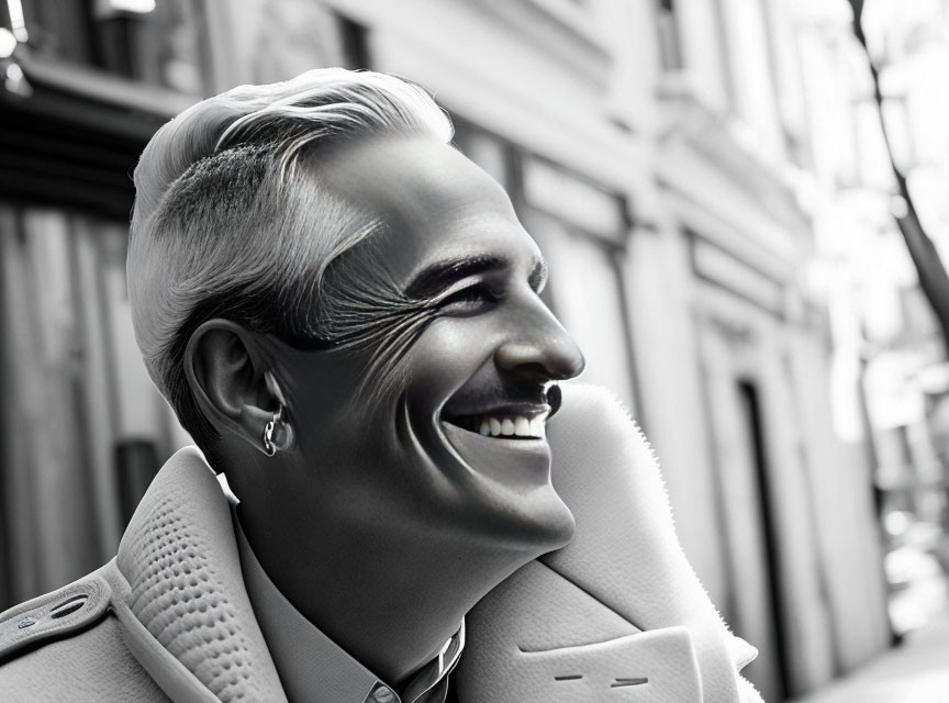 Smiling person with slicked-back hair in monochrome portrait