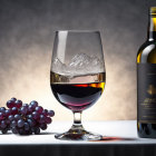 Whiskey glass with ice, bottle, grapes on table, dramatic textured background