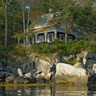 Stone cottage with blue door nestled by river & cliffs