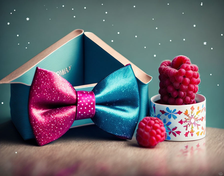 Colorful bow tie, book, tape roll, and raspberries on whimsical snowy background