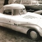 Silver Art Deco Vehicle on Cobblestone with Onlookers