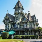 Victorian-style house with woodwork, turrets, and porch under stormy sky