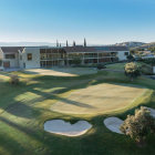 Tranquil sunrise scene of a golf course with clubhouse, sand traps, and rolling greens