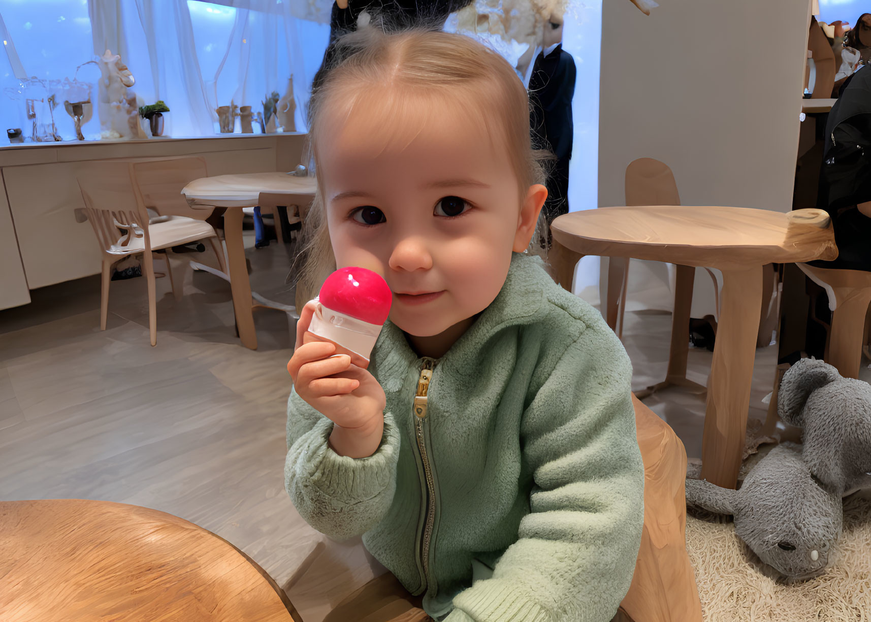 Child with ponytail holds red lollipop in bright room