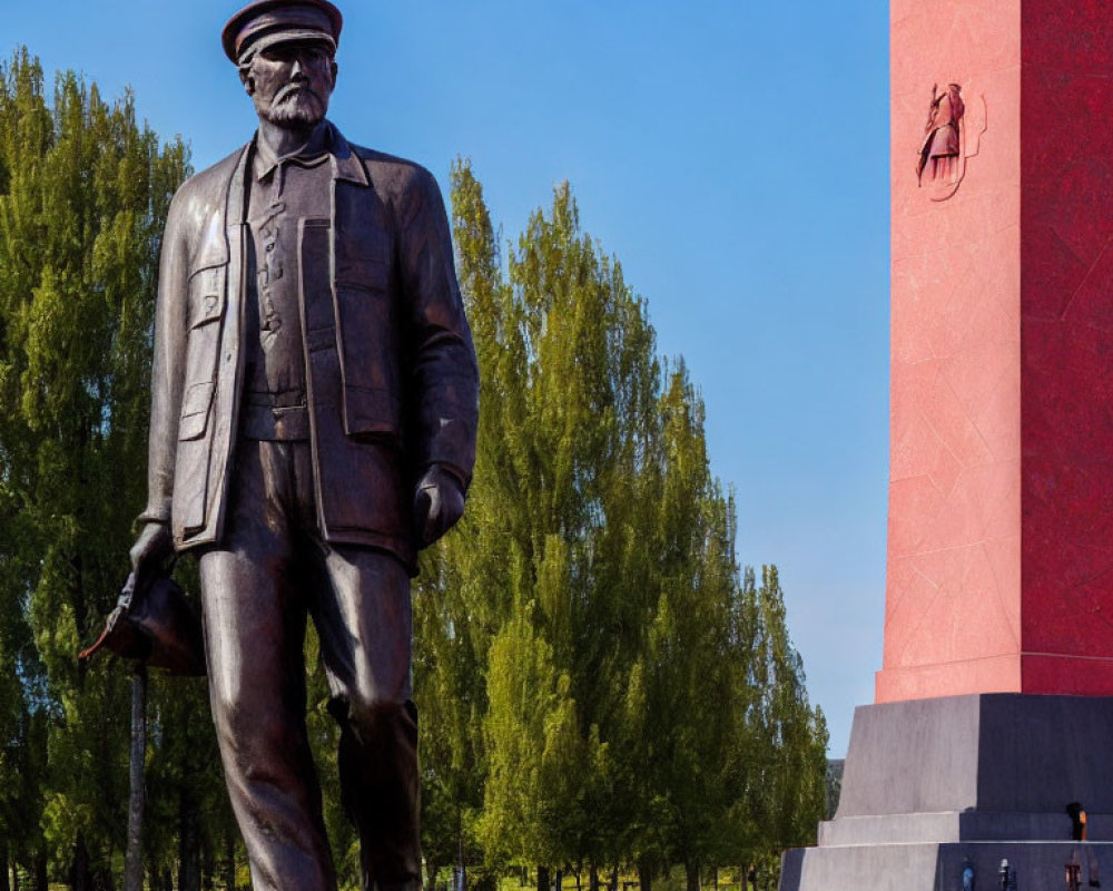 Military statue and red obelisk in green park setting