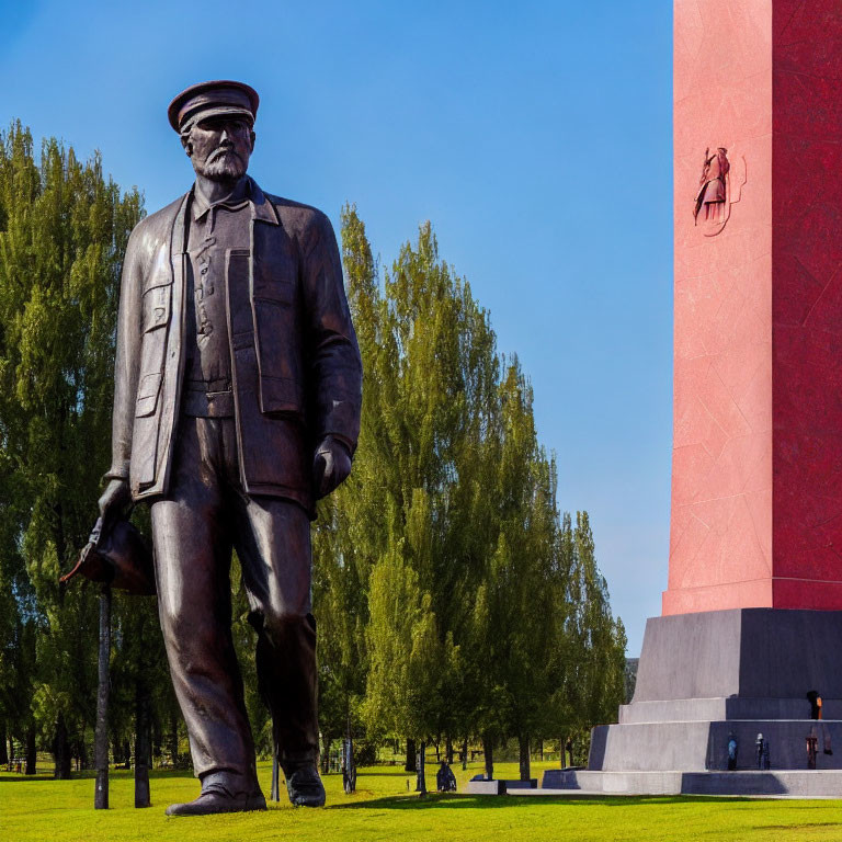 Military statue and red obelisk in green park setting