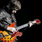 Musician playing electric guitar in black leather jacket and glasses