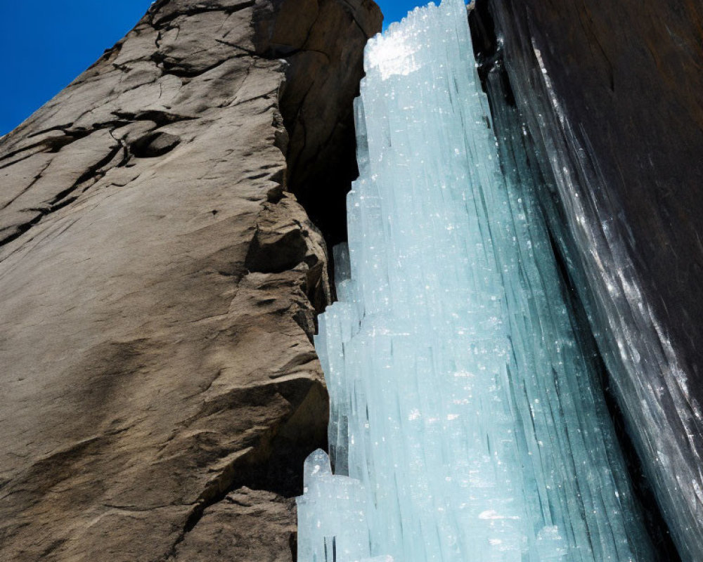 Rocky Cliff with Blue Ice Crystals Against Clear Blue Sky