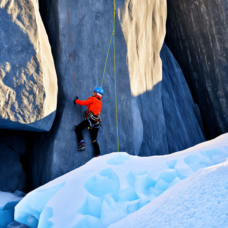 Climber in Orange Helmet Ascends Icy Cliff with Ice Axes