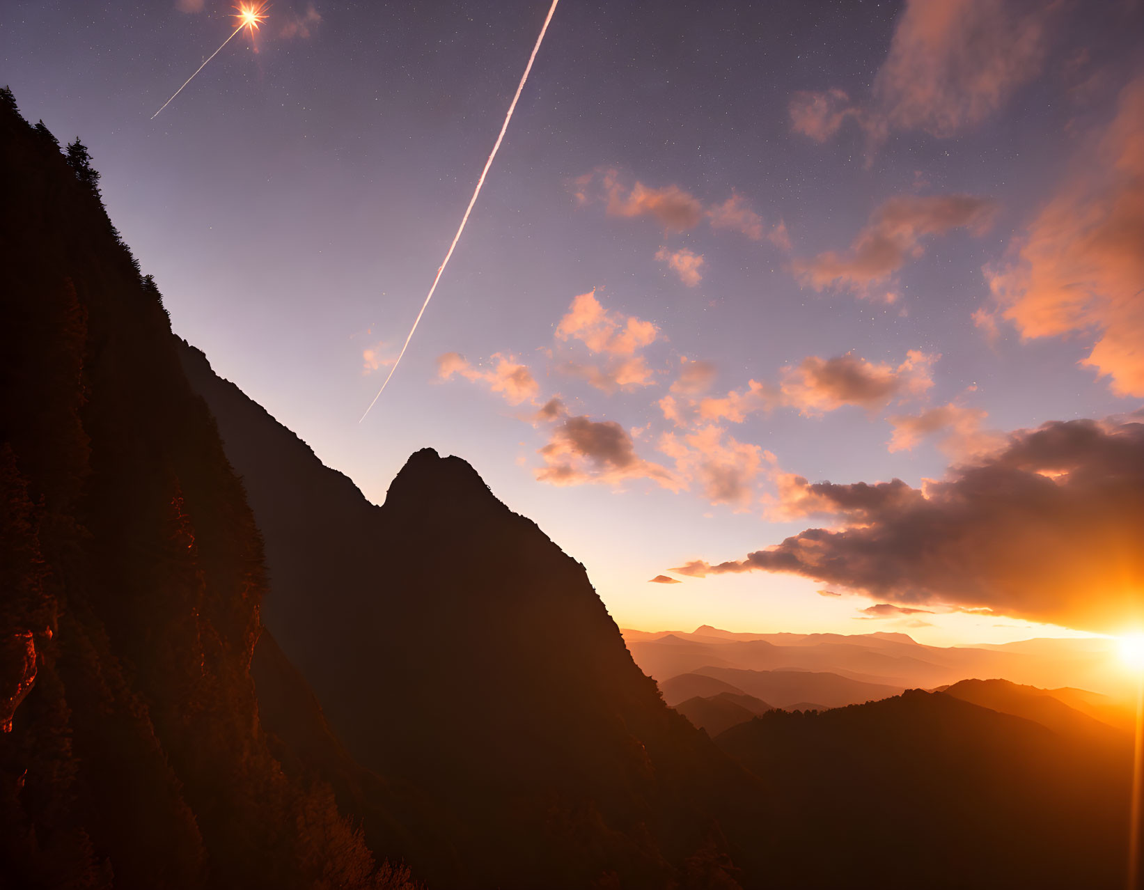 Scenic sunset over mountains with stars and shooting star in twilight sky