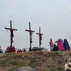 Scene of three individuals crucified on a hill with onlookers - solemn atmosphere